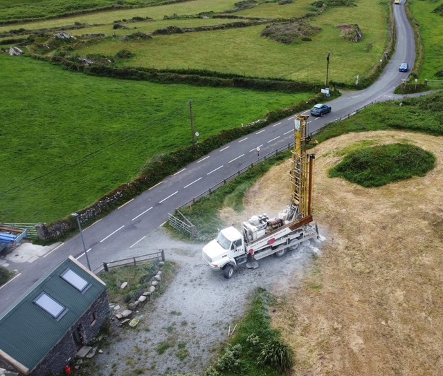 Aerial view of a well drilling rig at work in the Irish countryside near a stone-walled field